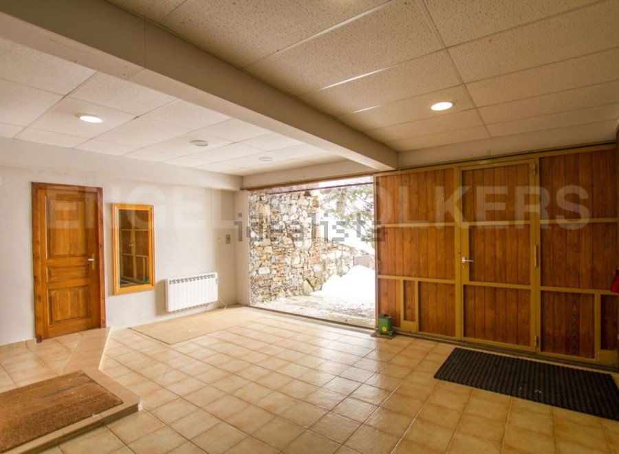This spacious property boasts a large garage with wooden doors, providing ample storage space.