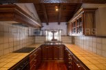 Rustic kitchen with wooden beams and tiled countertops.