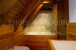 Charming attic bathroom with wooden walls and beams, featuring a bathtub and shower.
