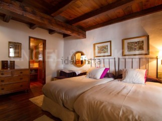 Charming rustic bedroom with wooden beams and exposed ceiling.