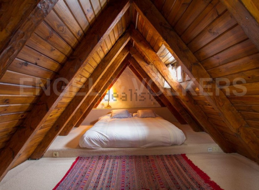 Cosy attic bedroom with wooden beams and a comfortable double bed.