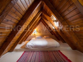 Cosy attic bedroom with wooden beams and a comfortable double bed.