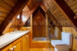 Charming attic bathroom with wood paneling, a shower stall, and a toilet.