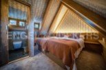 This stunning attic bedroom boasts a unique sloped ceiling with exposed wooden beams and stylish wallpaper.