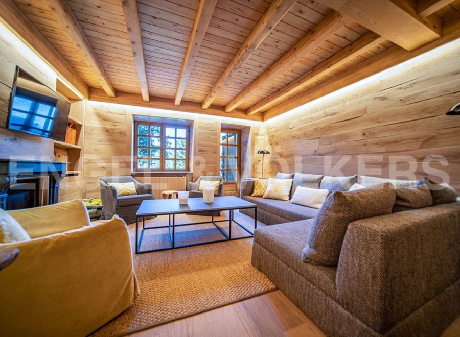 This stunning chalet boasts a spacious living area with exposed wooden beams and walls, creating a warm and inviting atmosphere.