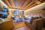 This stunning chalet boasts a spacious living area with exposed wooden beams and walls, creating a warm and inviting atmosphere.