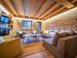 This stunning chalet boasts a spacious living area with exposed wooden beams and walls, creating a warm and inviting atmosphere.