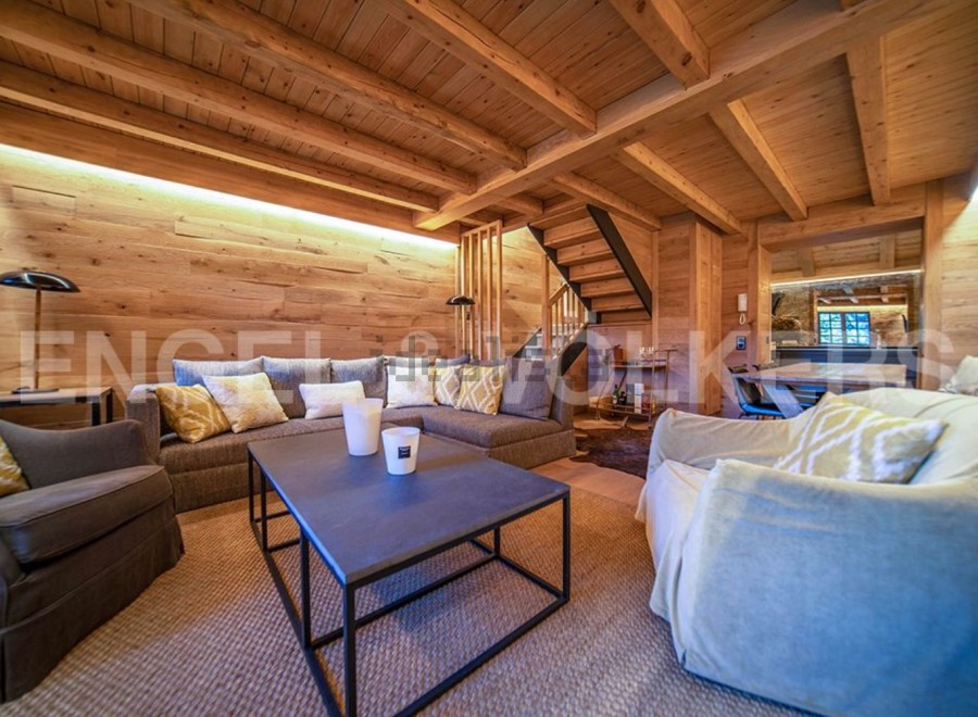 This stunning chalet boasts a spacious living area with exposed wooden beams and a cozy atmosphere.