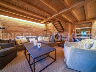 This stunning chalet boasts a spacious living area with exposed wooden beams and a cozy atmosphere.