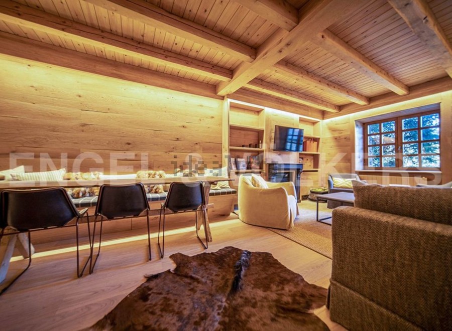This stunning chalet boasts a spacious open-plan living area with exposed wooden beams and a cozy fireplace.