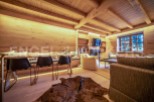 This stunning chalet boasts a spacious open-plan living area with exposed wooden beams and a cozy fireplace.
