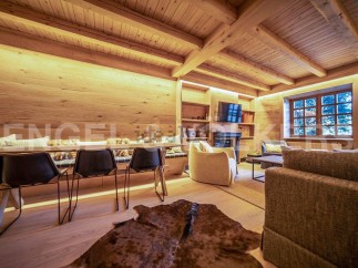This stunning chalet boasts a spacious open-plan living area with exposed wooden beams and a cozy fireplace.