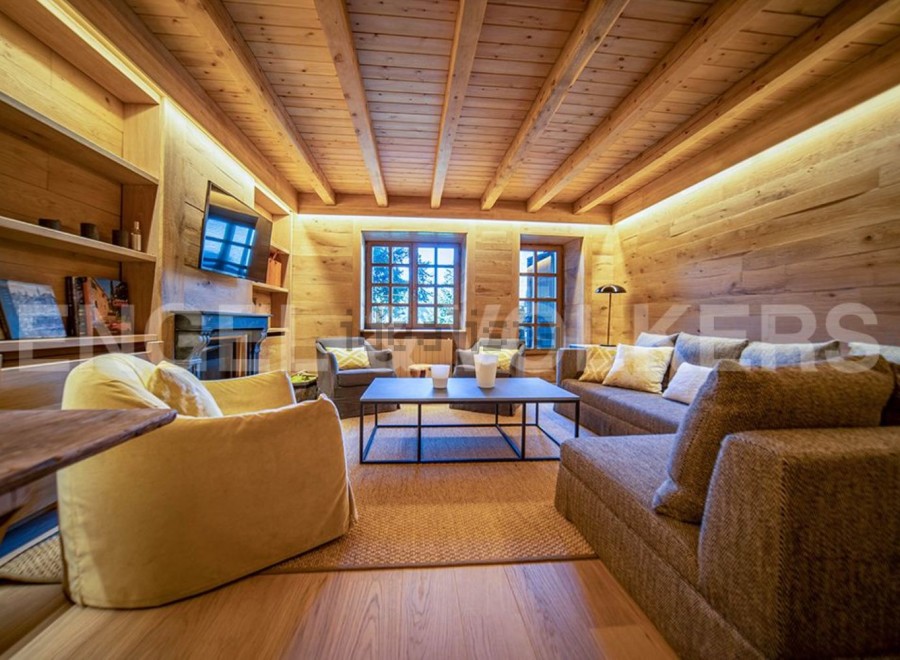This stunning chalet boasts a spacious living area with a cozy fireplace, large windows offering breathtaking views, and a sophisticated design that blends rustic charm with modern elegance.