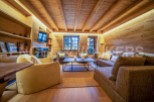 This stunning chalet boasts a spacious living area with a cozy fireplace, large windows offering breathtaking views, and a sophisticated design that blends rustic charm with modern elegance.