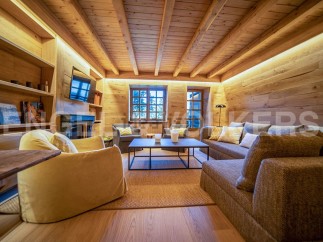 This stunning chalet boasts a spacious living area with a cozy fireplace, large windows offering breathtaking views, and a sophisticated design that blends rustic charm with modern elegance.