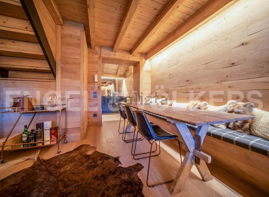 This stunning chalet boasts a unique wooden interior with exposed beams and a cozy built-in bench seating area.