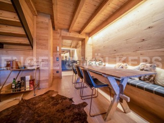 This stunning chalet boasts a unique wooden interior with exposed beams and a cozy built-in bench seating area.