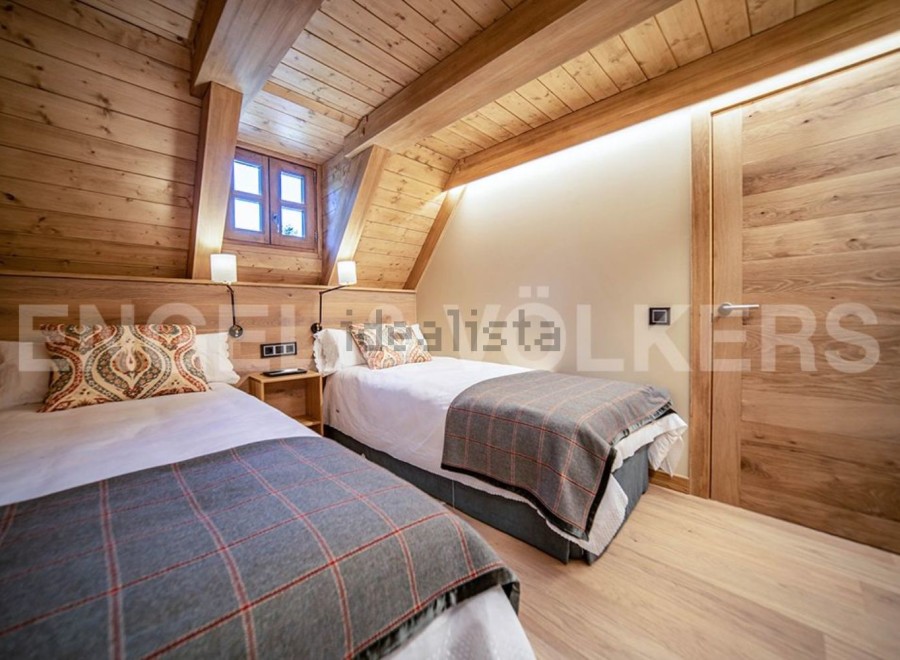 Cozy attic bedroom with twin beds, wooden beams, and a rustic feel.
