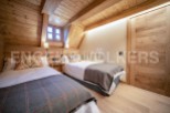 Cozy attic bedroom with twin beds, wooden beams, and a rustic feel.