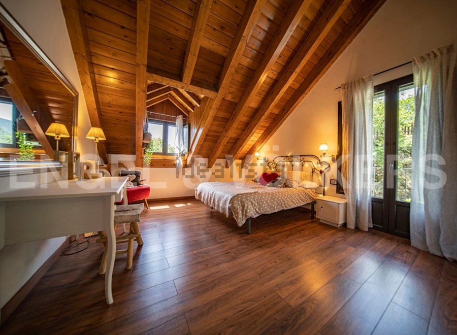 Charming attic bedroom with wooden beams, hardwood floors, and a cozy atmosphere.