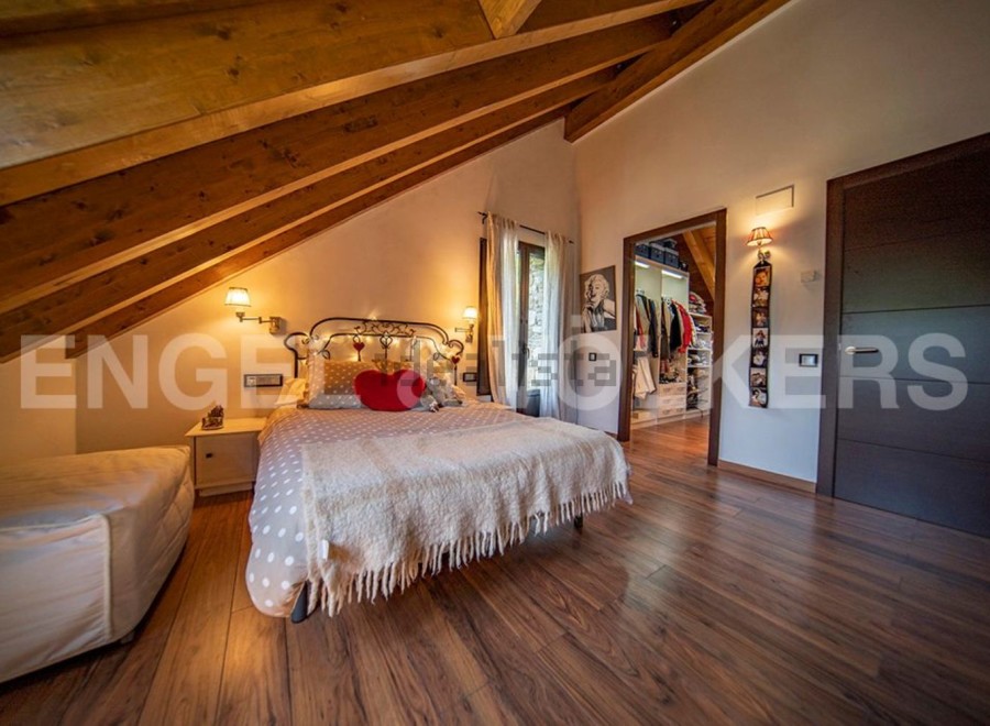 Cosy attic bedroom with wooden beams, featuring a double bed and ample closet space.