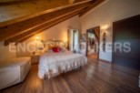 Cosy attic bedroom with wooden beams, featuring a double bed and ample closet space.