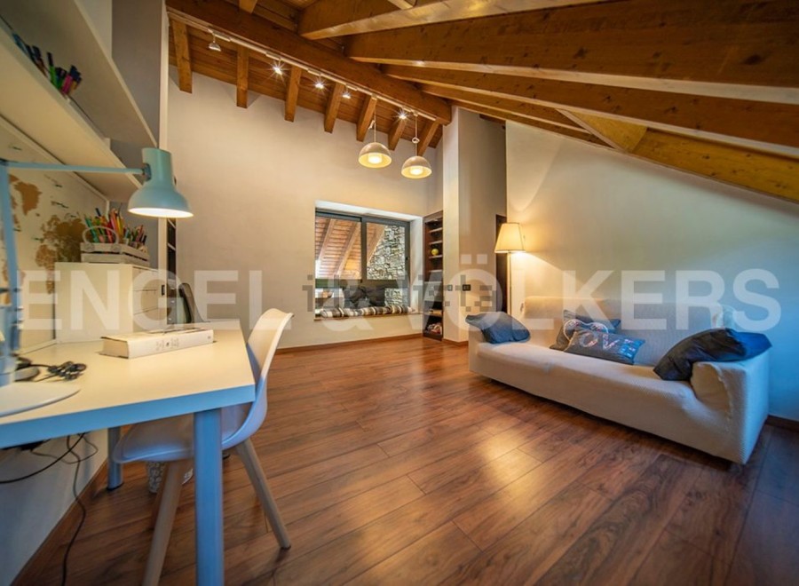 This attic room boasts a stunning wooden beam ceiling and large window, creating a bright and airy atmosphere.