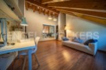 This attic room boasts a stunning wooden beam ceiling and large window, creating a bright and airy atmosphere.