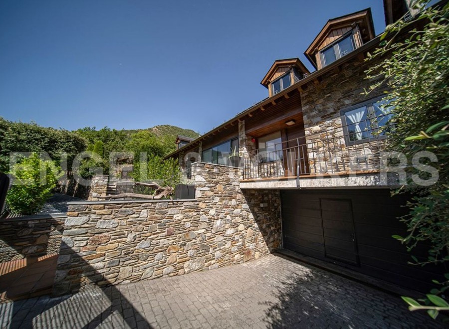 This stunning stone house boasts a spacious garage, a charming balcony, and large windows offering breathtaking views.