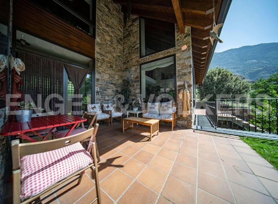 This stunning property boasts a spacious outdoor patio perfect for relaxation and entertaining, featuring comfortable seating and a charming red table set.