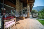 This stunning property boasts a spacious outdoor patio perfect for relaxation and entertaining, featuring comfortable seating and a charming red table set.