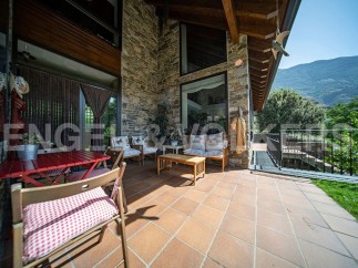 This stunning property boasts a spacious outdoor patio perfect for relaxation and entertaining, featuring comfortable seating and a charming red table set.