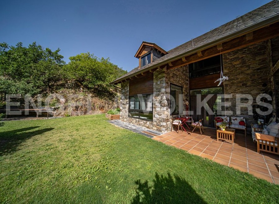 This stunning stone house boasts a spacious patio perfect for outdoor entertaining, surrounded by a lush green lawn.