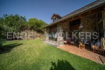 This stunning stone house boasts a spacious patio perfect for outdoor entertaining, surrounded by a lush green lawn.
