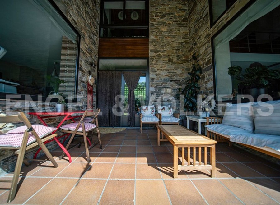 This stunning property boasts a spacious patio perfect for outdoor relaxation, featuring comfortable seating and a charming red table set.