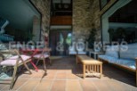 This stunning property boasts a spacious patio perfect for outdoor relaxation, featuring comfortable seating and a charming red table set.