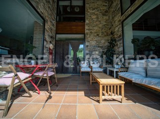 This stunning property boasts a spacious patio perfect for outdoor relaxation, featuring comfortable seating and a charming red table set.