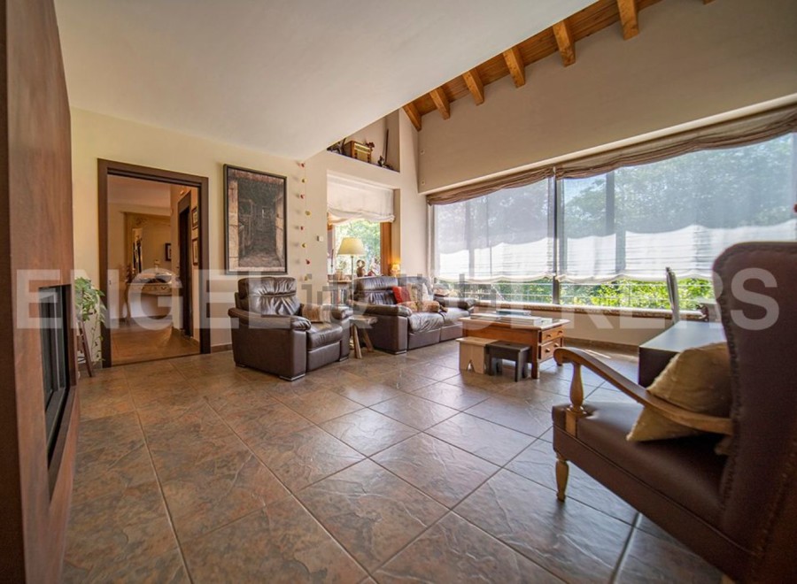 This stunning property boasts a spacious living area with large windows offering abundant natural light and views of the lush greenery.