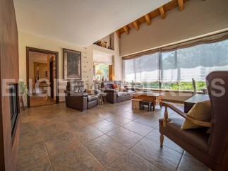 This stunning property boasts a spacious living area with large windows offering abundant natural light and views of the lush greenery.