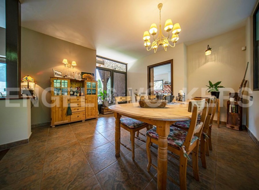This charming dining room boasts a rustic wooden table and chairs, complemented by a light-toned wooden cabinet and a stylish chandelier.