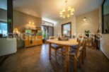 This charming dining room boasts a rustic wooden table and chairs, complemented by a light-toned wooden cabinet and a stylish chandelier.