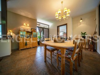 This charming dining room boasts a rustic wooden table and chairs, complemented by a light-toned wooden cabinet and a stylish chandelier.