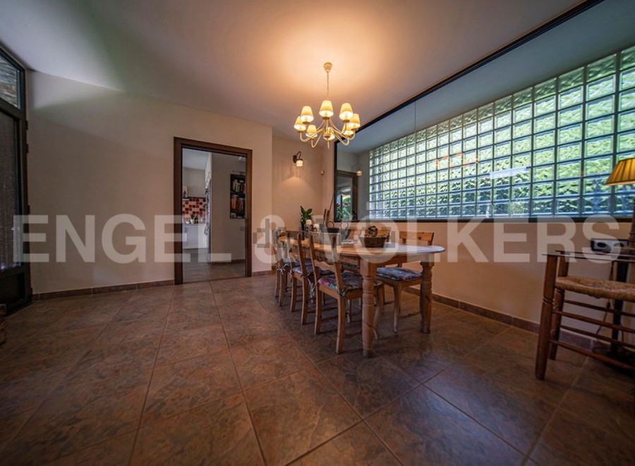 Charming dining area with rustic wooden table and chairs, complemented by a unique glass block window offering ample natural light.