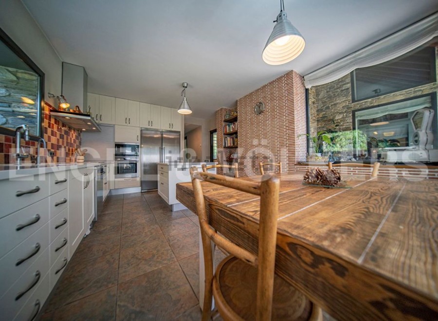 Rustic kitchen with wooden dining table and modern appliances.