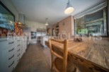 Rustic kitchen with wooden dining table and modern appliances.
