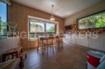 Rustic kitchen with brick feature wall, large windows overlooking garden, and white shaker-style cabinets.