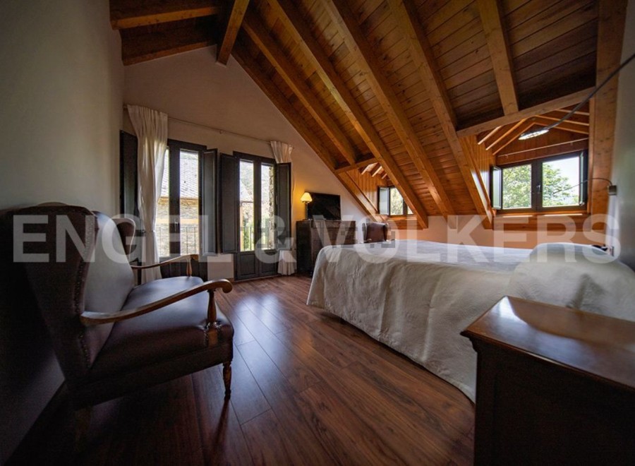 Charming attic bedroom with wooden beams, offering a cozy and rustic atmosphere.