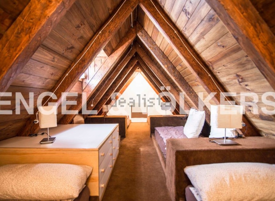 Charming attic bedroom with exposed wooden beams and built-in storage.