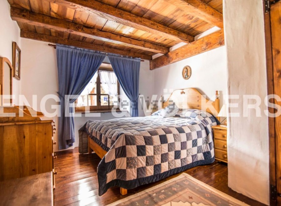 Charming rustic bedroom with wooden beams, hardwood floors, and a patchwork quilt.