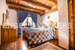 Charming rustic bedroom with wooden beams, hardwood floors, and a patchwork quilt.